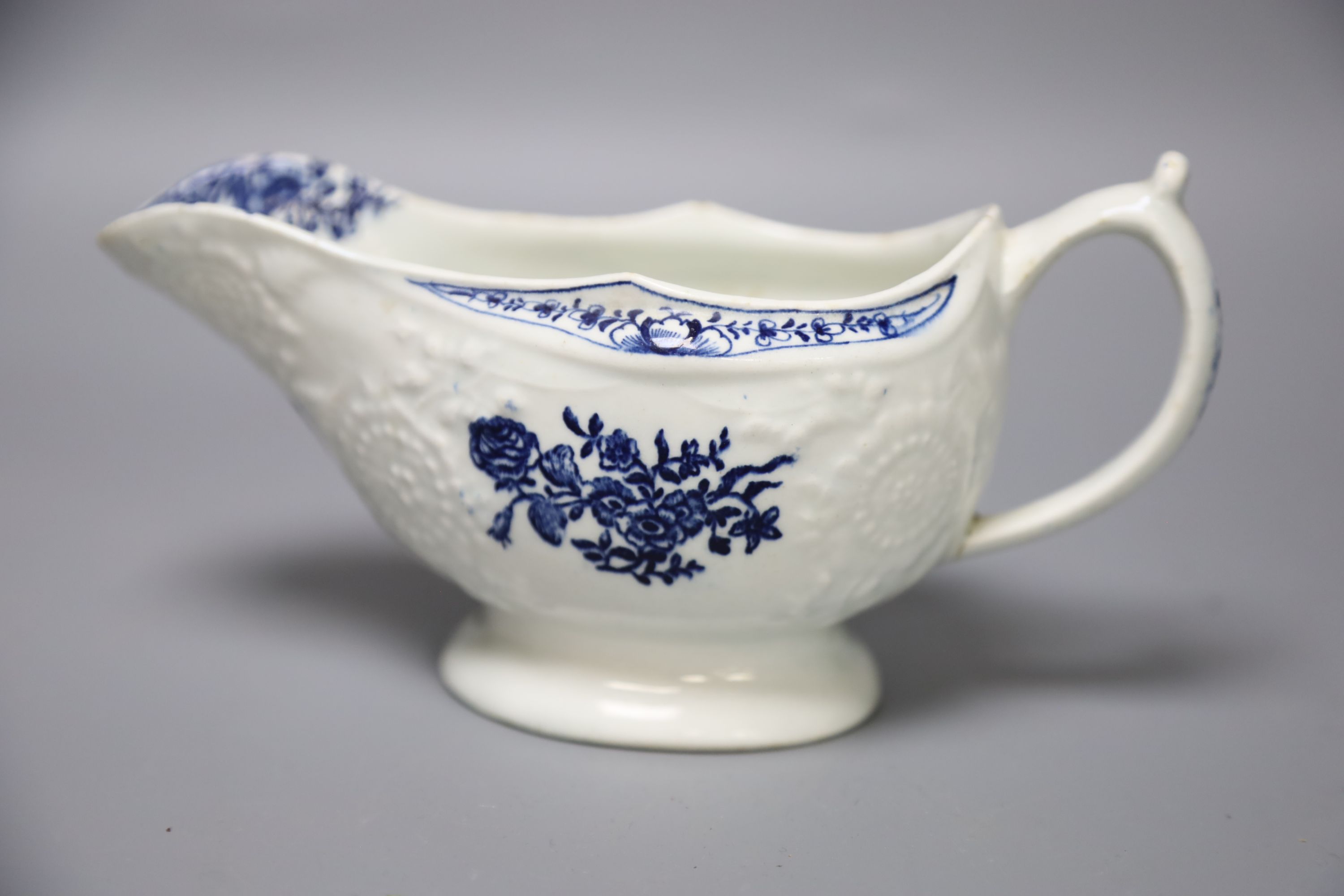 An 18th century Lowestoft floral moulded sauceboat flower in blue to each side and inside base, length 20cm